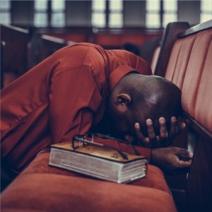 black man praying at pew